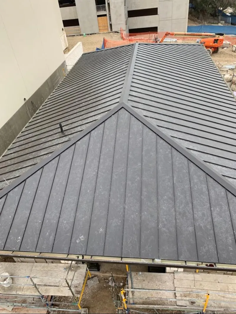 Commercial metal roof construction with crane equipment in Atwater